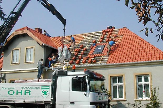 Kran hebt Material auf einen Dachstuhl während der Sanierung