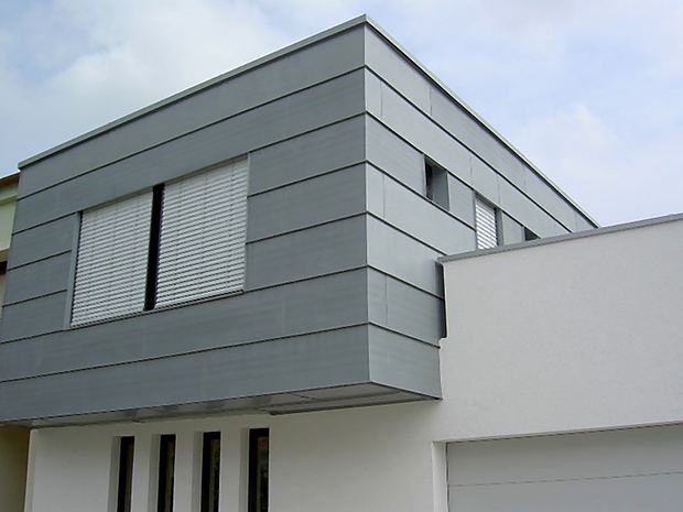 Grau verkleideter Erker über einem weiß verputzten Haus