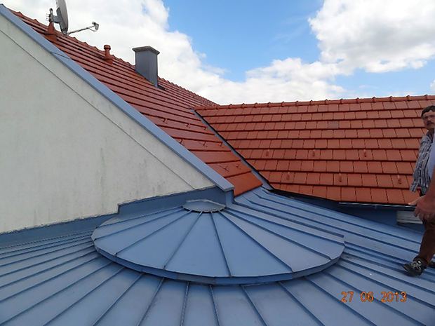 Rundes Turmdach mit Blecheindeckung neben roter Ziegeldeckung