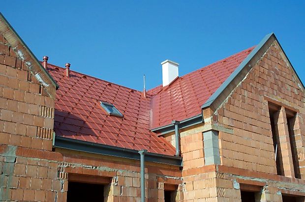 Neu gedecktes Ziegeldach auf einem Rohbau mit Kamin und Kehlen